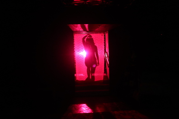 the shadow of a character doing a strip sequence projected onto a wavy pink curtain